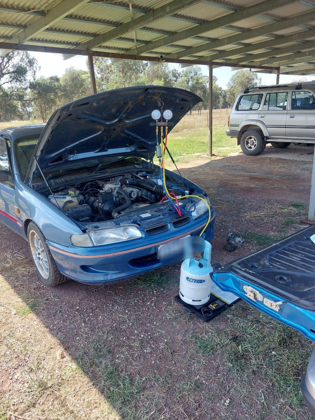 Blue car AC regas service in shed